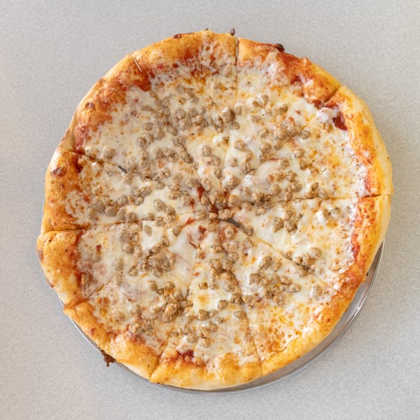 A whole sausage pizza, cut into slices, on a metal tray.