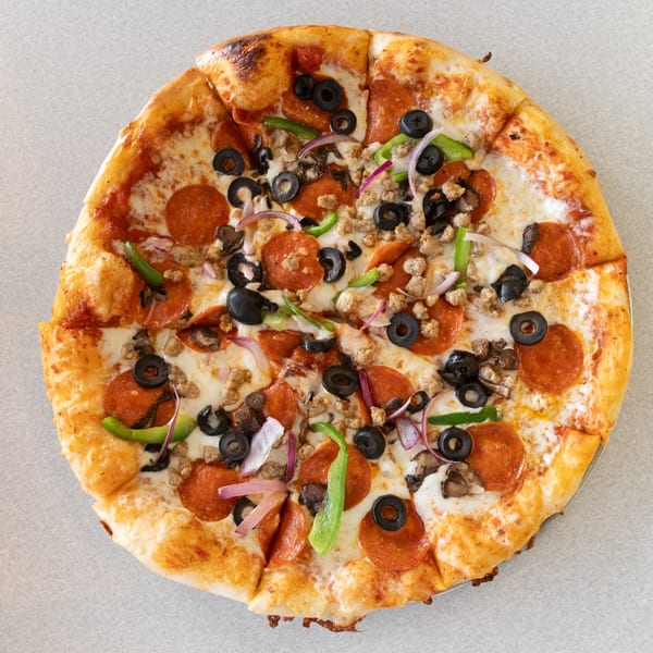 A whole pizza with pepperoni, sausage, black olives, green peppers, mushrooms, and red onions.