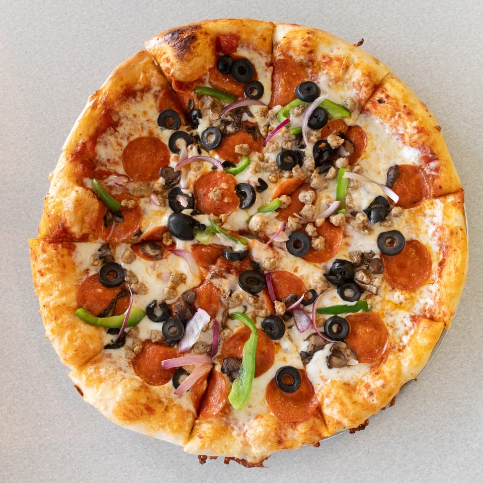 A whole pizza with pepperoni, sausage, black olives, green peppers, mushrooms, and red onions.